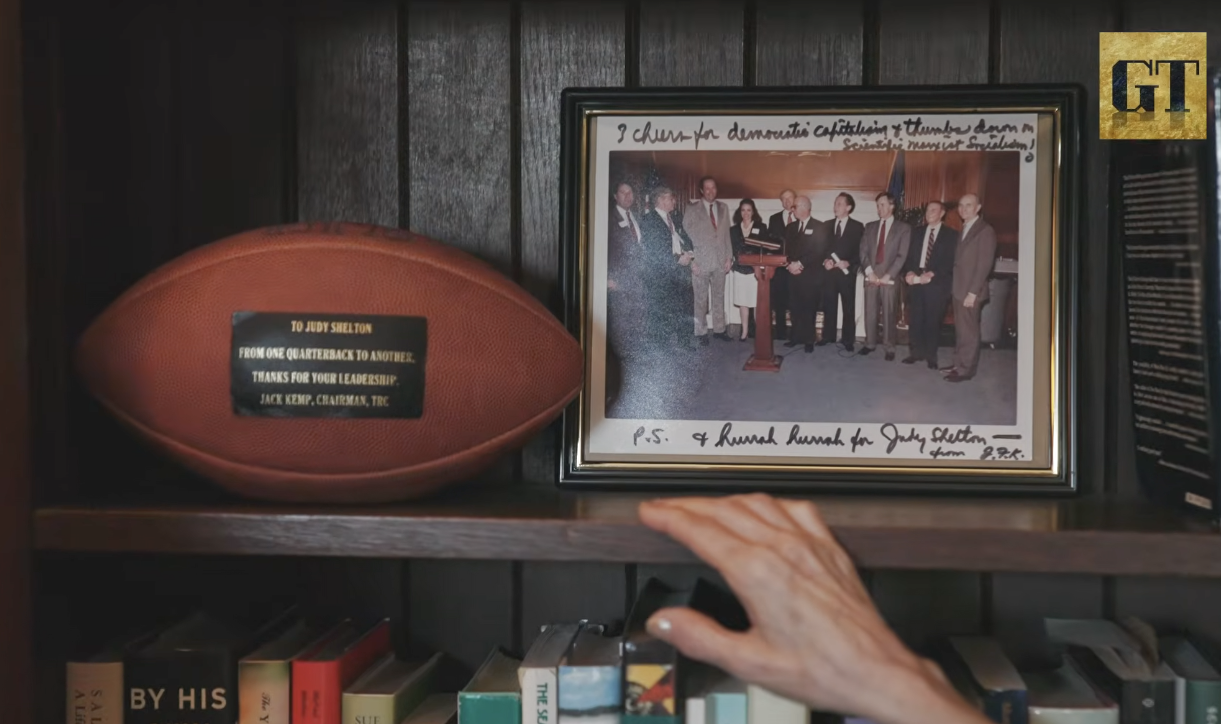 Framed photograph signed by Jack Kemp and a football inscribed to Judy Shelton, displayed on Dr. Shelton's shelf